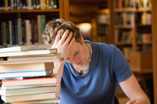 手托着脑袋在图书馆里学习的男人