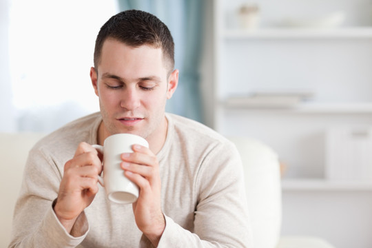 男子在客厅里双手拿着杯子