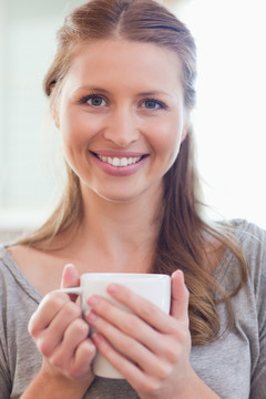 微笑的年轻女人捧着咖啡杯