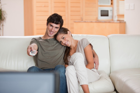 年轻夫妇在沙发上一起看电视