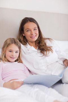 女孩和妈妈在卧室里读一本书