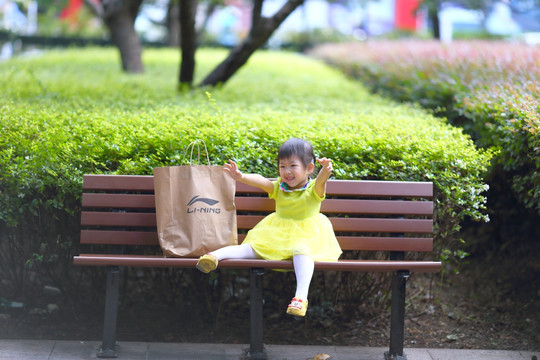 小女孩坐在公园的长椅上