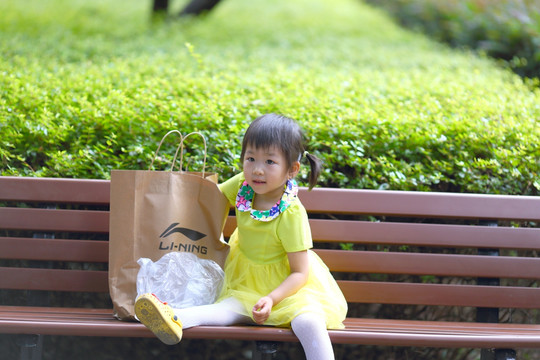 小女孩坐在公园的长椅上