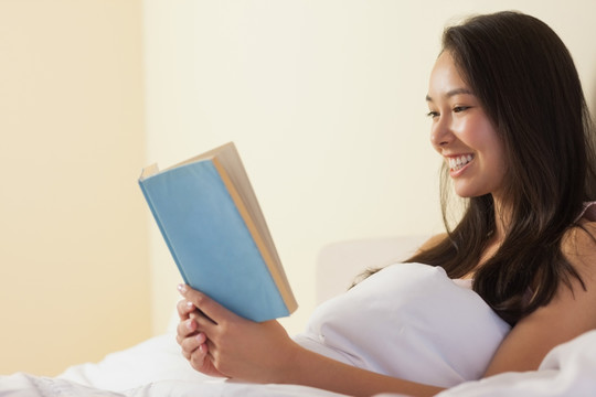 躺在床上看着书的女人