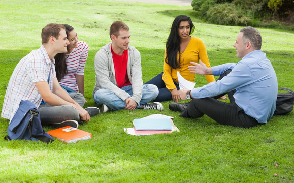 学生坐在校园的草坪上听讲师上课