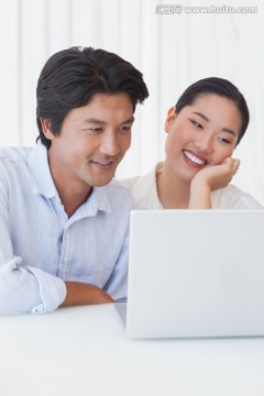夫妇微笑着看着笔记本电脑