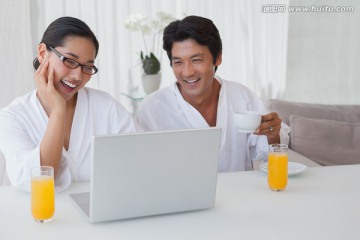夫妇看着笔记本电脑微笑着