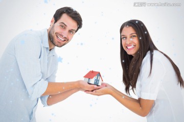 夫妇微笑着捧着房屋模型
