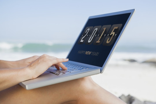 坐在沙滩上使用笔记本电脑的女人