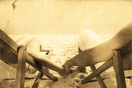 躺在沙滩椅上牵着手的夫妇