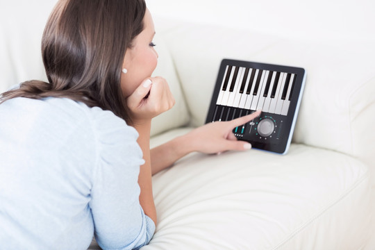 在使用平板电脑弹钢琴的女人