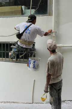 粉刷工人悬空给墙壁粉刷