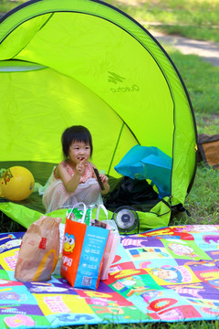 在帐篷里吃零食的小女孩