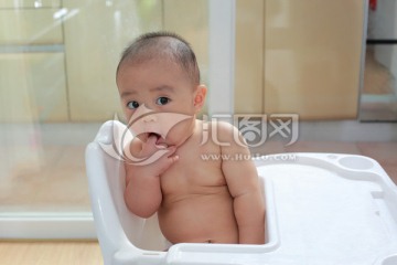 胖胖婴儿坐着手指放嘴里看镜头