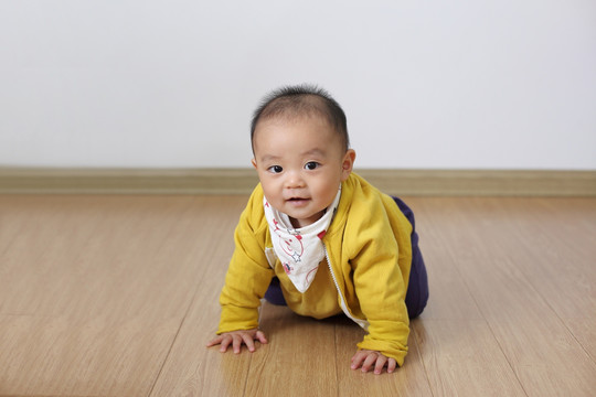 打扮时尚婴儿双手撑着仿木地板笑
