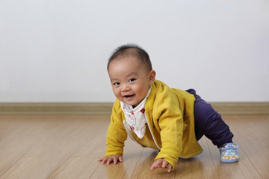 时尚婴儿双手撑着仿木地板爬行