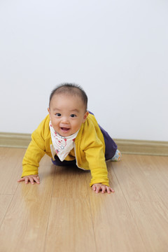 打扮时尚的婴儿在仿木地板上爬行