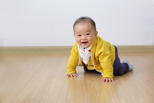 打扮时尚的婴儿在仿木地板上爬行