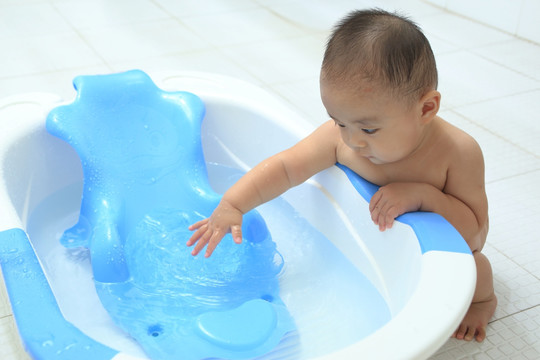 胖胖婴儿扶着洗澡盆蹲着玩水