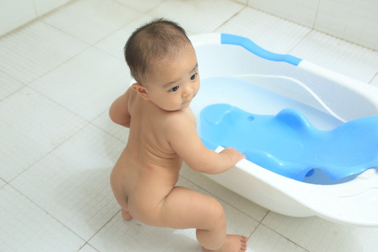 胖胖婴儿扶着洗澡盆站着看外面
