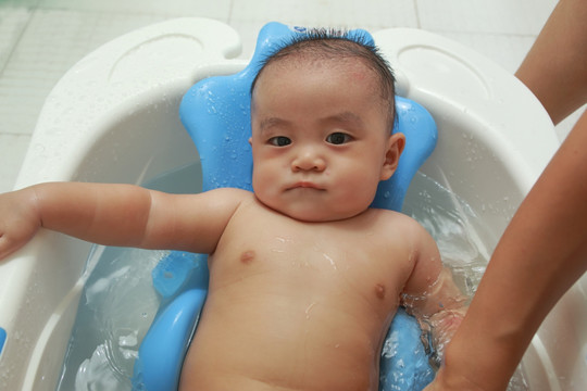 胖胖婴儿躺在洗澡盆里不情愿洗澡