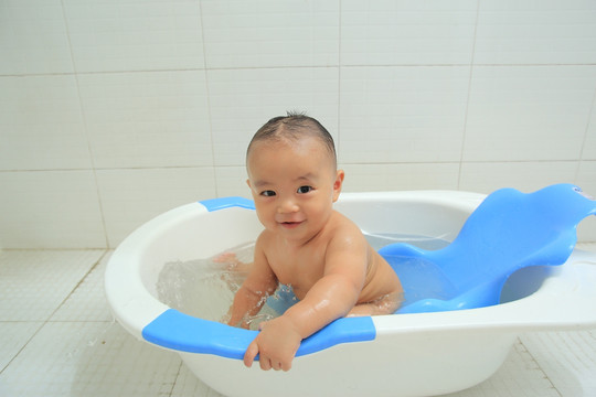胖胖婴儿坐洗澡盆里对着镜头微笑
