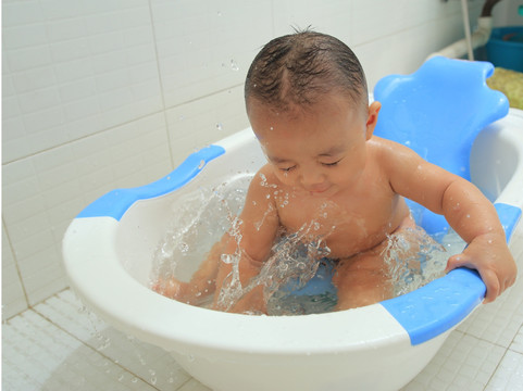 胖胖婴儿坐洗澡盆里兴奋的玩水