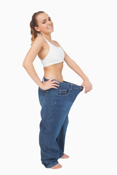 减肥成功的女人拉着牛仔裤腰