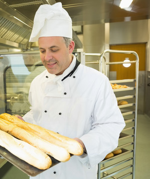 成熟的厨师拿着长棍面包