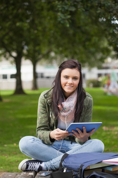 坐在草坪上用平板电脑的女学生