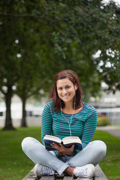 微笑的学生坐在长凳上看书