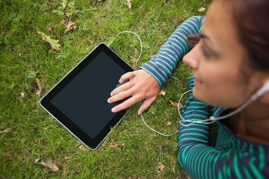 趴在草地上用平板电脑听歌的女生