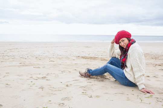 穿着温暖的衣服坐在沙滩上的女人