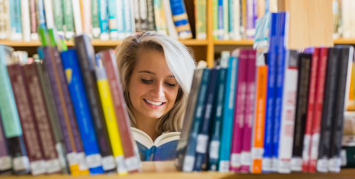 微笑的女大学生在图书馆看书