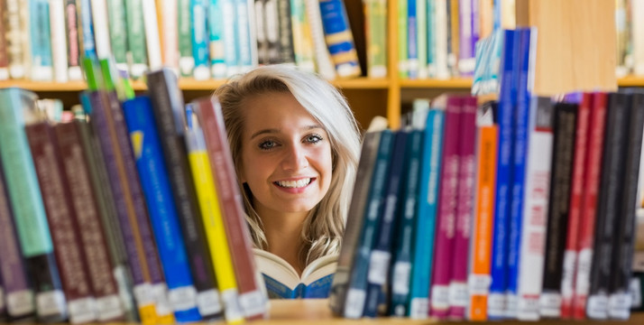 微笑的女大学生在图书馆看书