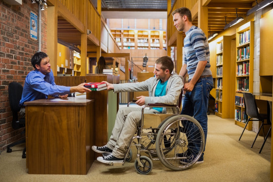 在图书馆柜台前坐轮椅的男人