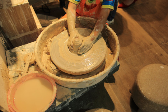 一个小孩在旋转的拉胚机制作陶瓷