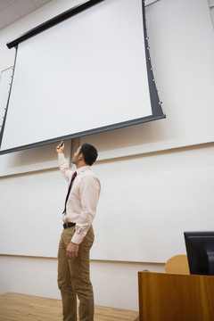 在演讲厅里指着投影屏幕的男教授