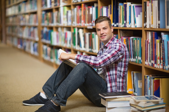 坐在图书馆地板上看书的男大学生
