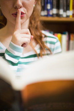 拿着书的女学生手指放在嘴唇上