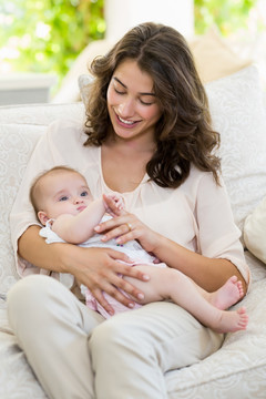 微笑的母亲抱着婴儿坐在沙发上