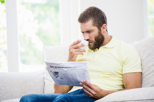 男人在客厅里喝咖啡看报纸