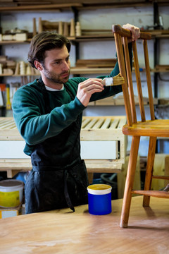 在椅子上涂抹油漆的男木匠