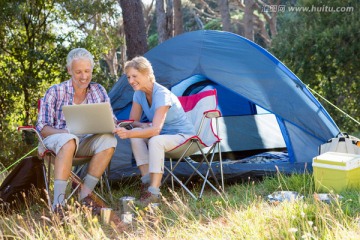 坐在帐篷外使用笔记本电脑的夫妇