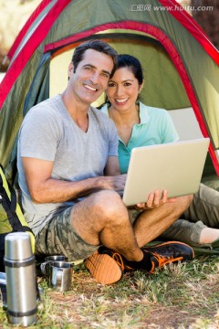 夫妇微笑着拿着一台笔记本电脑