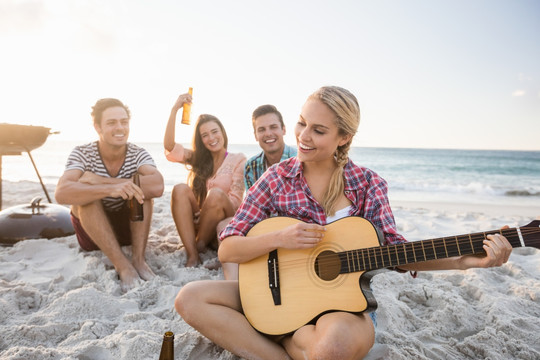 坐在沙滩上弹吉他的女人