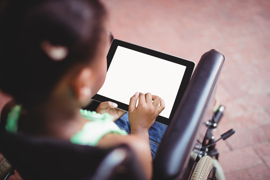 坐在轮椅上使用平板电脑的女孩