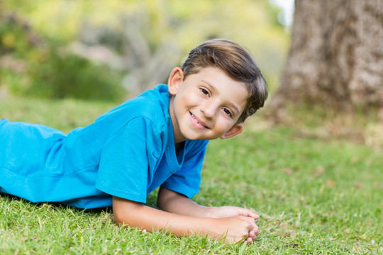 微笑的小男孩趴在草地上