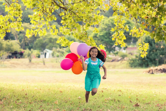拿着气球泡在公园里奔跑的小女孩