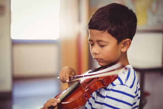 在教室里拉小提琴的小男孩